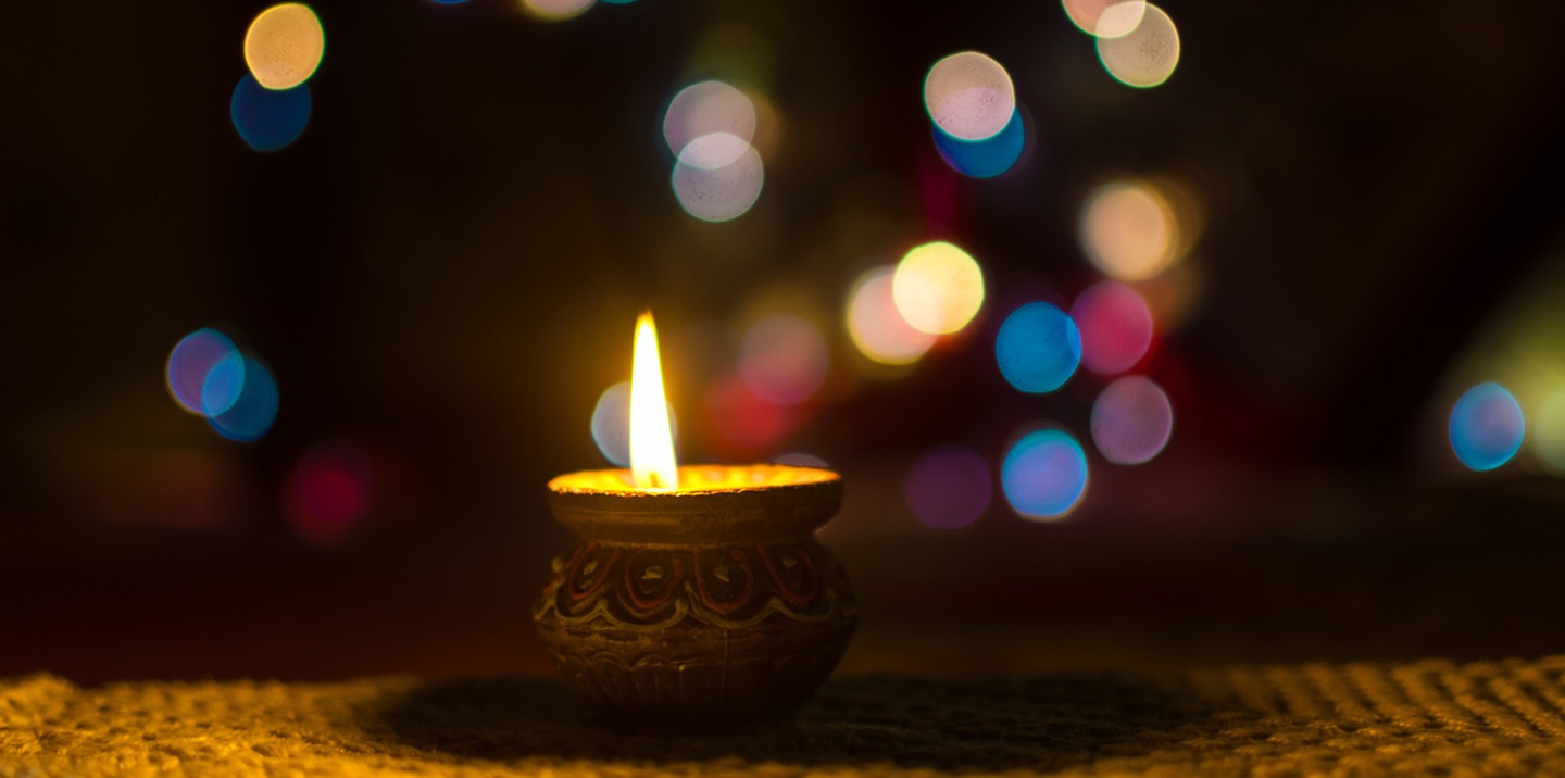 A row of lit clay diya lamps glowing in the dark for Diwali